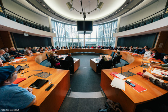 Die teilnehmenden der Konferenz Sitzen im Konferenzsaal in einem äußeren und einem inneren Kreis an runden Tischen.