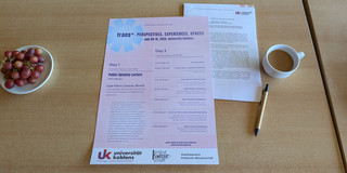 table with dish of grapes, conference poster, pen, and a cup of coffee