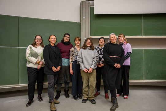 The members of the teaching area stand in front of the blackboard in a lecture hall.