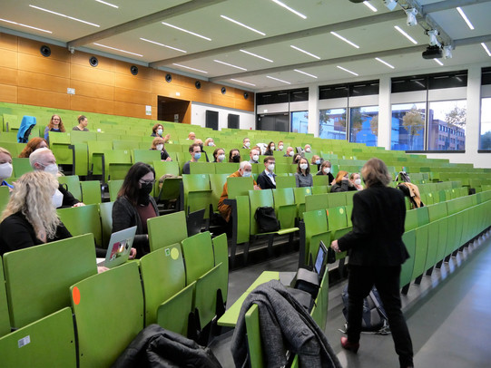 Das Foto zeigt die Zuhörer bei der Antrittsvorlesung von Prof. Dr. Mona Motakef. Sie sitzen mit Abstand und Mund-Nasen-Schutz im Hörsaal.